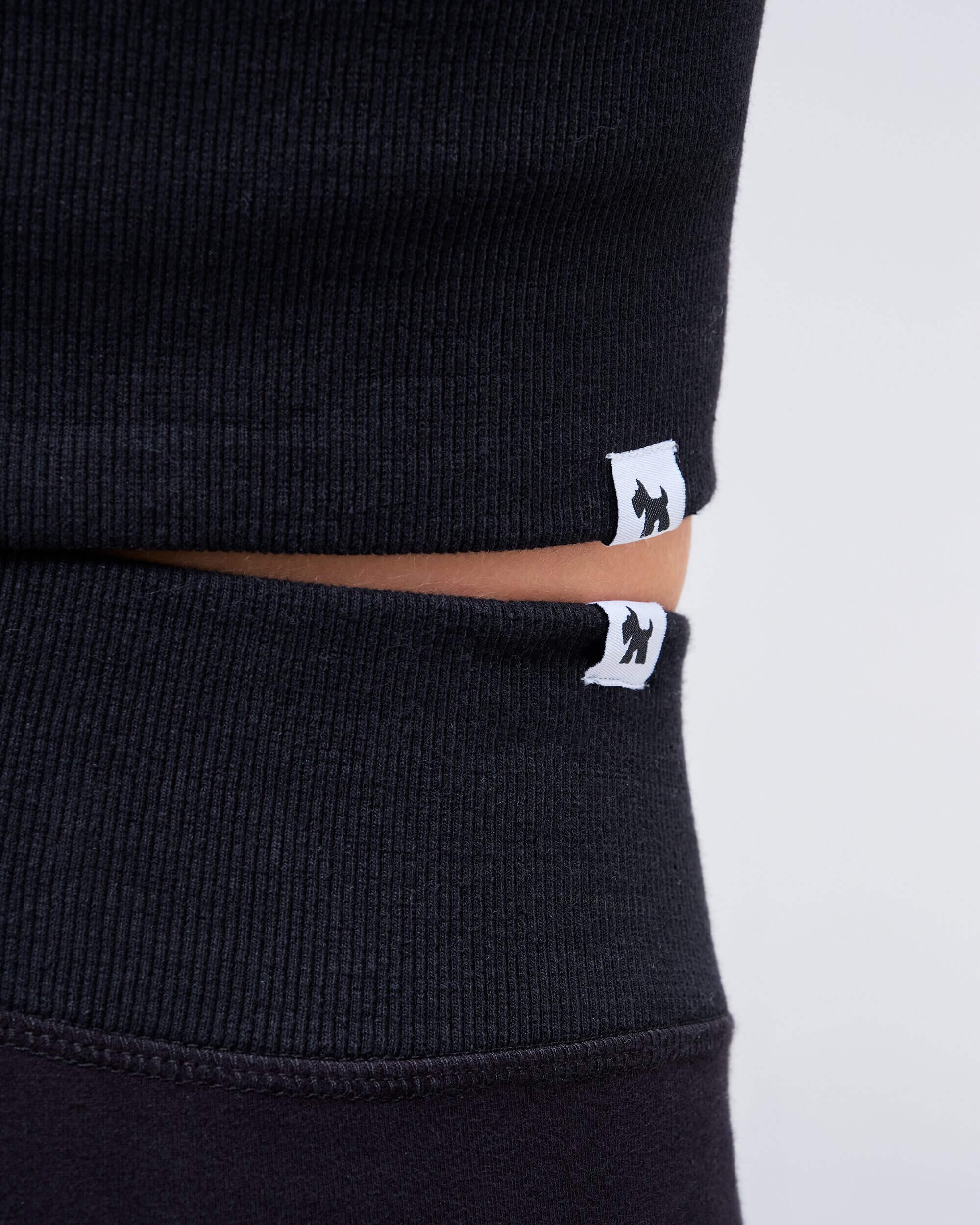 Edith fitted low rise flare pant in black, close-up of waistband logo detail