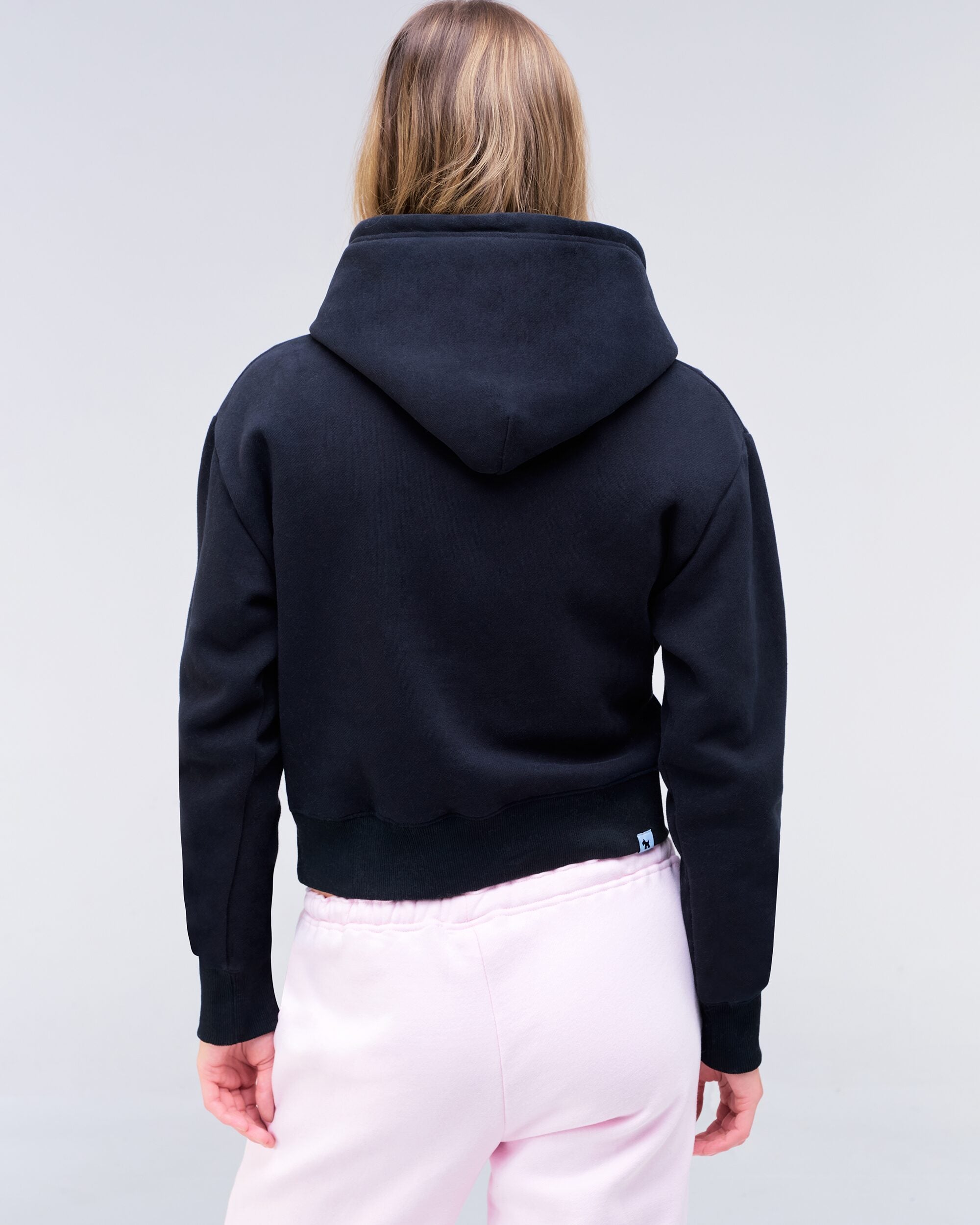 Emely cropped pullover hoodie in black with pink logo, full body back view