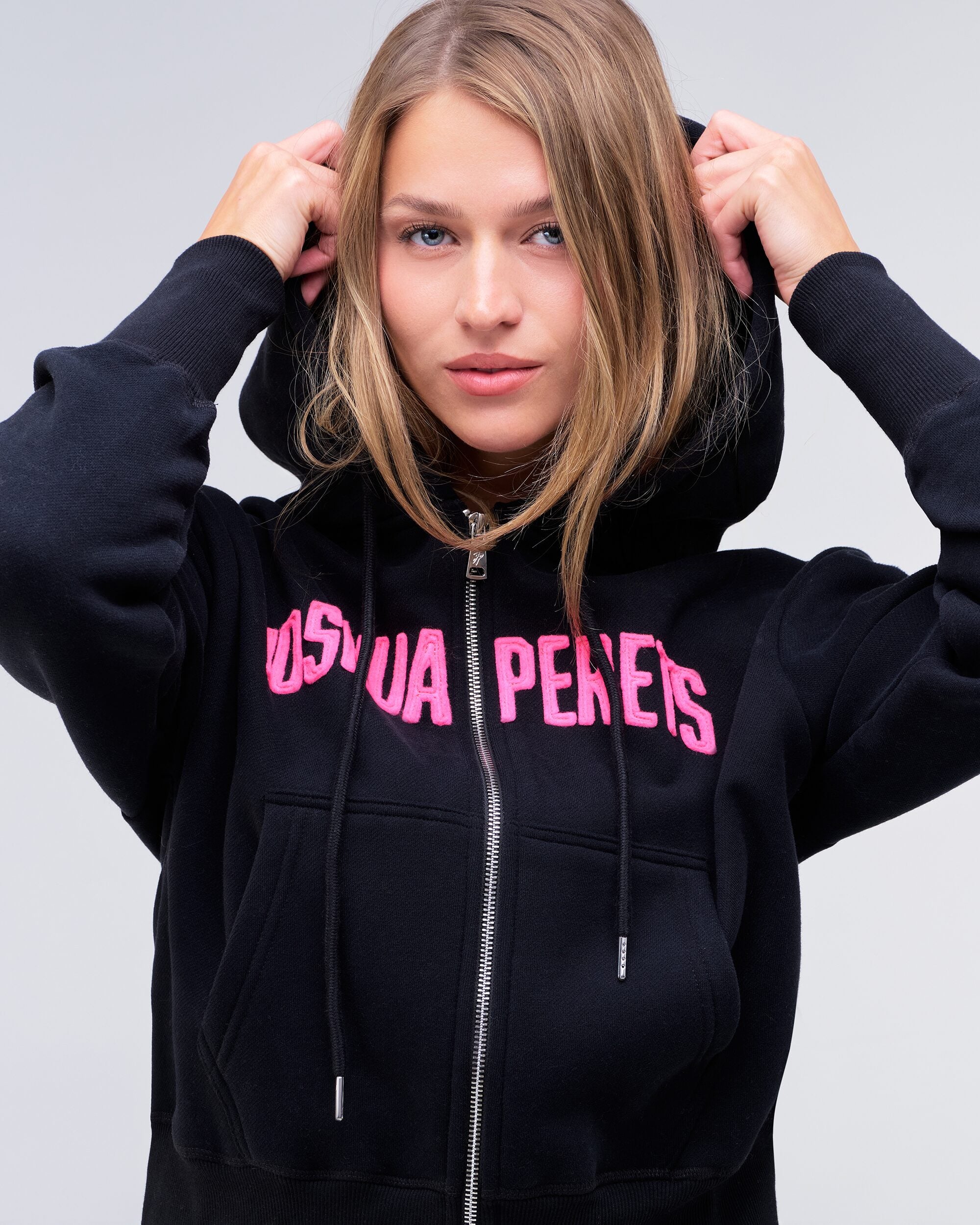 Paige relaxed-fit zip-up hoodie in black with pink logo, front view with hood up